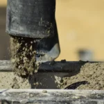 Wylewanie betonu do szamba betonowego, widoczna praca mieszarki i wypływ mieszanki